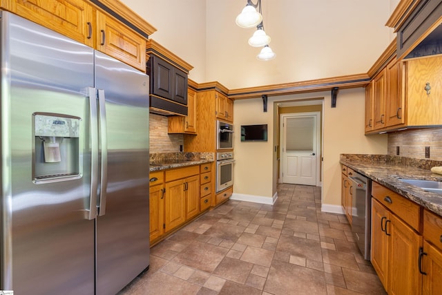 kitchen with dark stone counters, stainless steel appliances, hanging light fixtures, and tasteful backsplash