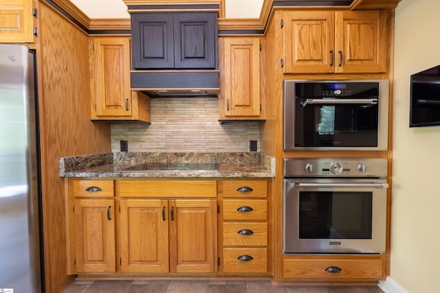 kitchen featuring ventilation hood, dark stone counters, stainless steel appliances, and tasteful backsplash