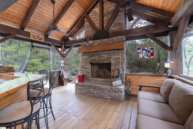 sunroom / solarium featuring wood ceiling, vaulted ceiling with beams, an outdoor stone fireplace, and ceiling fan