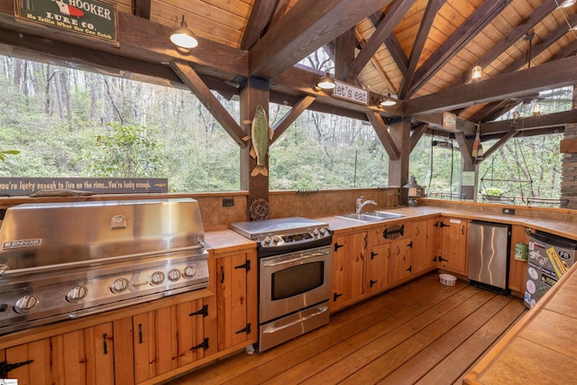 kitchen featuring vaulted ceiling with beams, appliances with stainless steel finishes, wooden ceiling, and sink