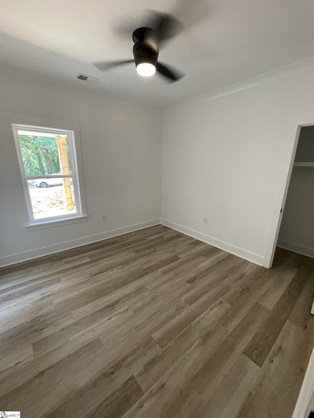 unfurnished bedroom with ornamental molding, dark hardwood / wood-style floors, ceiling fan, and a closet