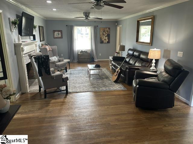 living room featuring ornamental molding, wood-type flooring, and ceiling fan