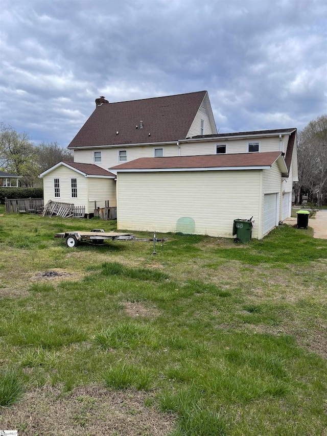 rear view of property with a garage and a lawn