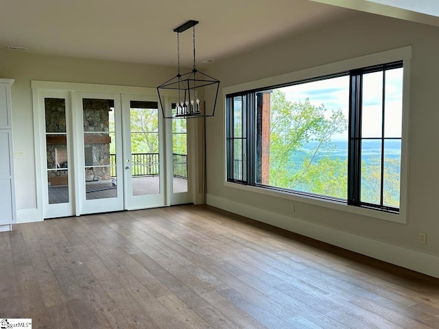 unfurnished dining area featuring light wood-type flooring and an inviting chandelier