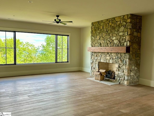 unfurnished living room featuring a fireplace, light wood-type flooring, and ceiling fan