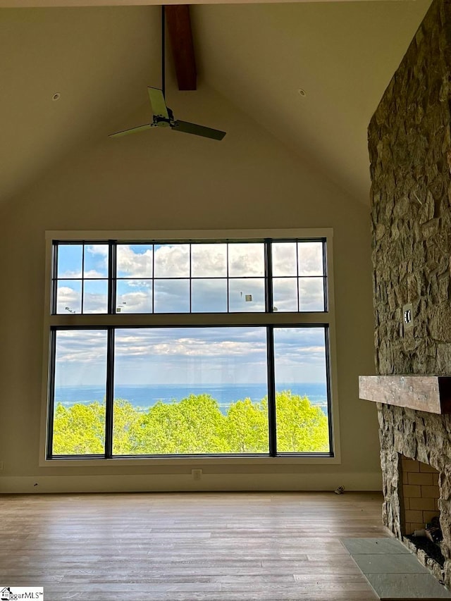 details with beamed ceiling, wood-type flooring, a stone fireplace, and ceiling fan