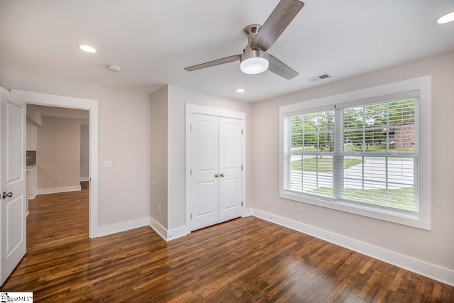 unfurnished bedroom with a closet, dark hardwood / wood-style flooring, and ceiling fan