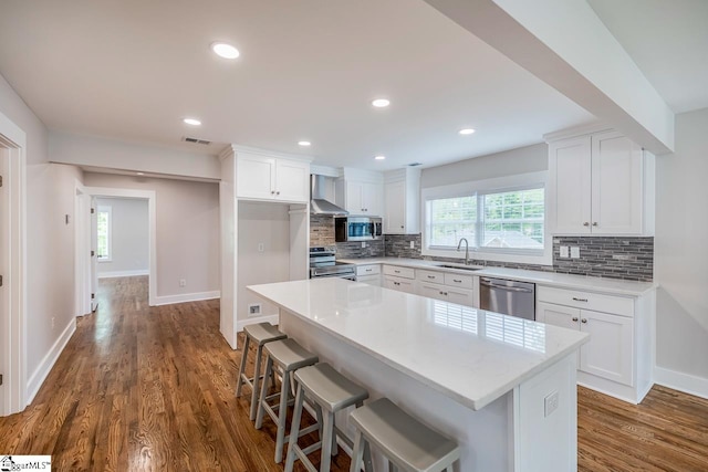 kitchen with white cabinets, sink, a center island, and stainless steel appliances