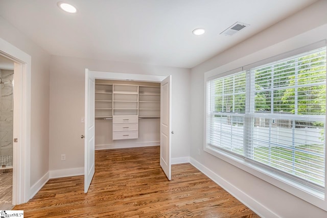 unfurnished bedroom featuring wood-type flooring, a closet, and multiple windows