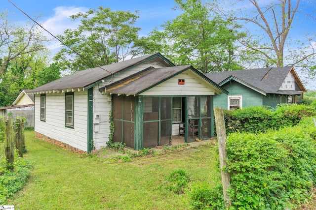 rear view of property featuring a yard and a sunroom