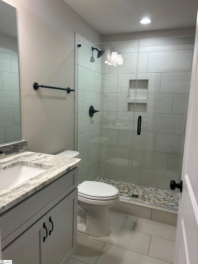 bathroom with toilet, tile patterned flooring, an enclosed shower, and vanity