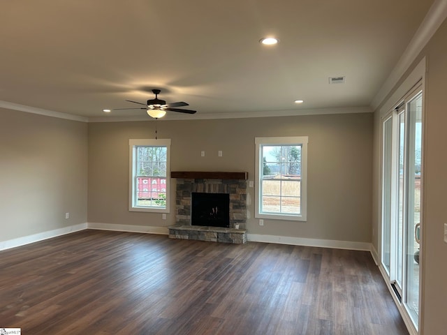 unfurnished living room with ceiling fan, dark wood-type flooring, a wealth of natural light, and a stone fireplace