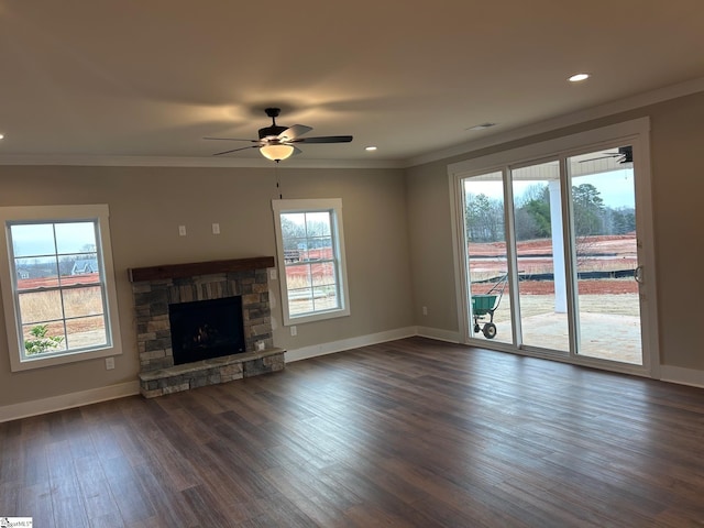 unfurnished living room with ceiling fan, dark hardwood / wood-style floors, crown molding, and a stone fireplace