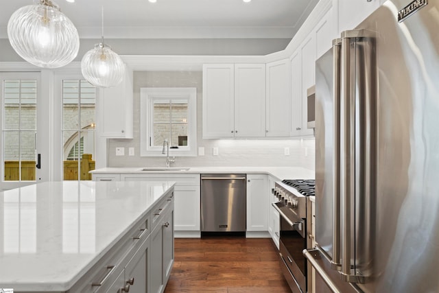 kitchen featuring high end appliances, white cabinetry, sink, and light stone counters