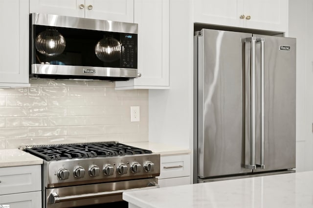 kitchen featuring light stone countertops, stainless steel appliances, and white cabinets