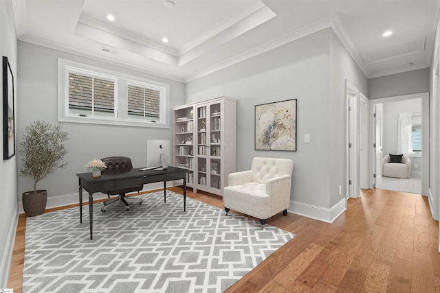 home office featuring hardwood / wood-style flooring, crown molding, and a raised ceiling