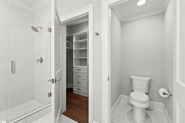 bathroom with a shower with shower door, ornamental molding, and toilet