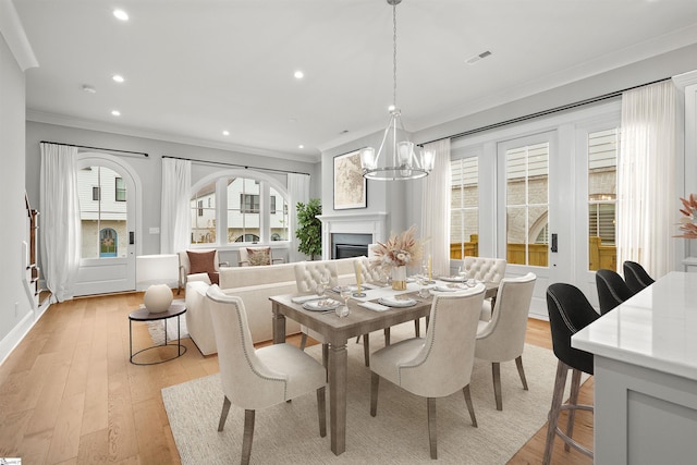 dining area with crown molding, a chandelier, and light wood-type flooring