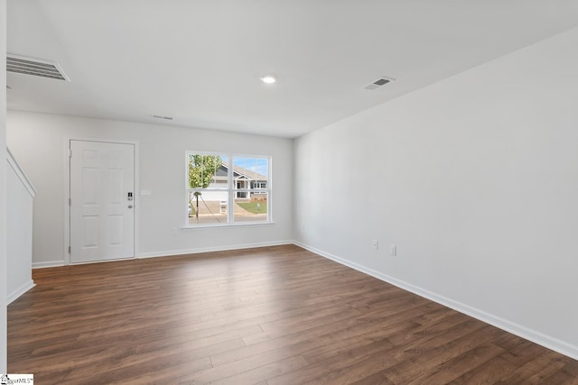 unfurnished room featuring dark wood finished floors, visible vents, and baseboards