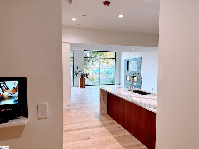 corridor with light hardwood / wood-style floors and sink