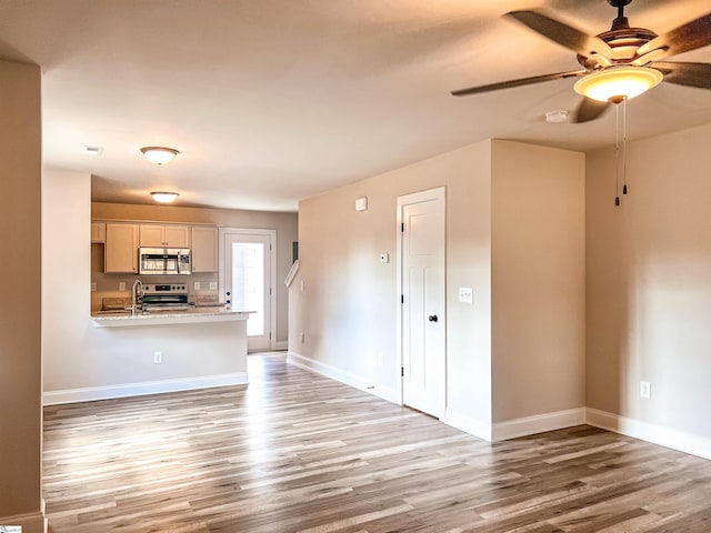 unfurnished living room with light hardwood / wood-style floors, ceiling fan, and sink