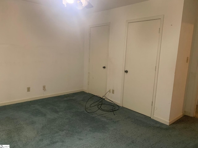 unfurnished bedroom featuring ceiling fan and dark carpet