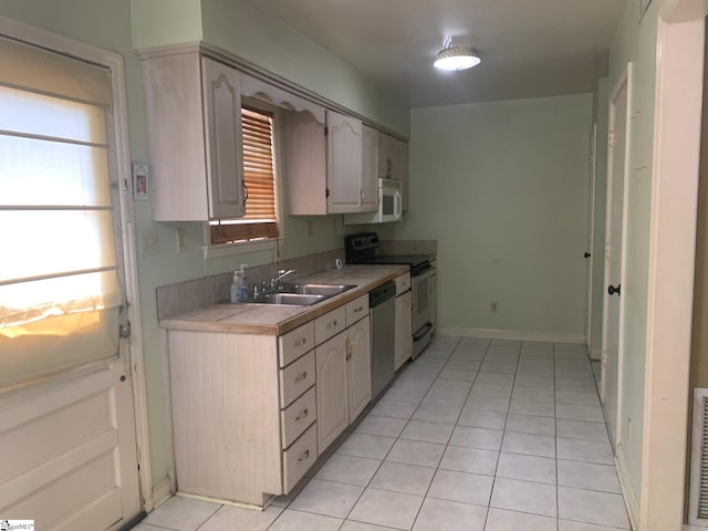 kitchen featuring range, dishwasher, sink, and light tile flooring