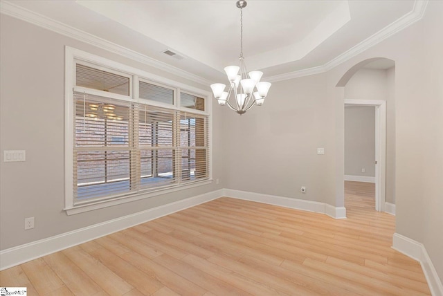 empty room featuring light hardwood / wood-style flooring, a raised ceiling, an inviting chandelier, and ornamental molding