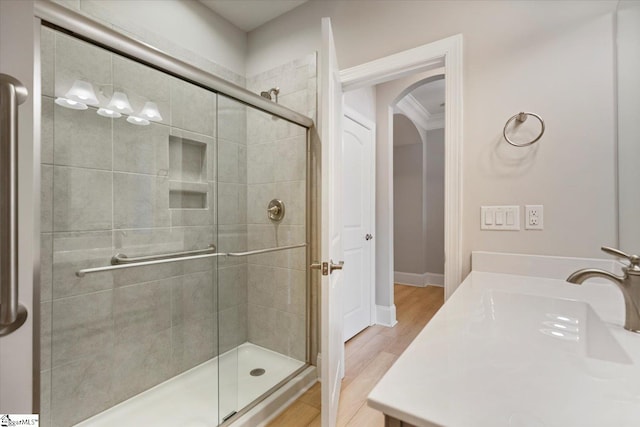 bathroom with walk in shower, crown molding, sink, and hardwood / wood-style flooring