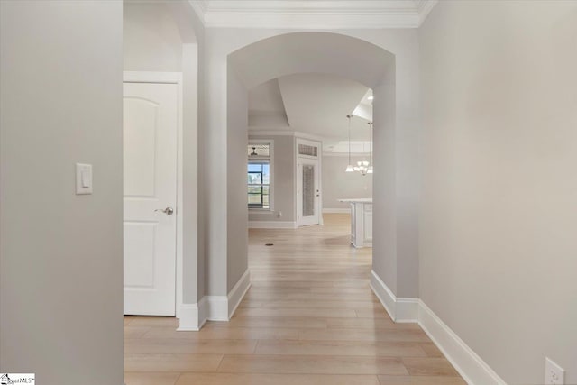 hallway featuring light hardwood / wood-style floors, an inviting chandelier, and crown molding