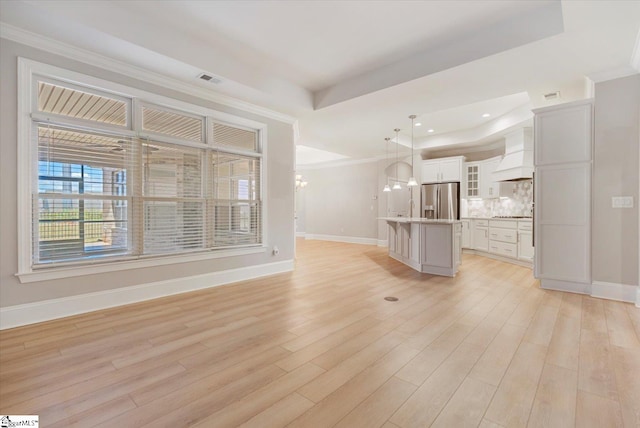 unfurnished living room featuring ornamental molding, light hardwood / wood-style flooring, and a raised ceiling