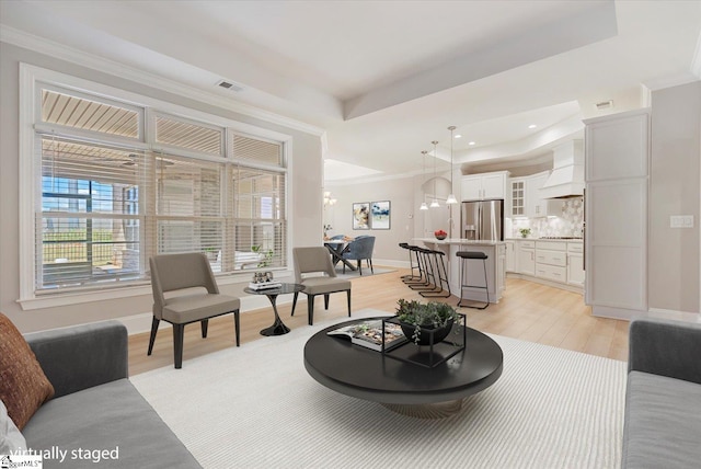 living room featuring ornamental molding, light hardwood / wood-style flooring, and a raised ceiling