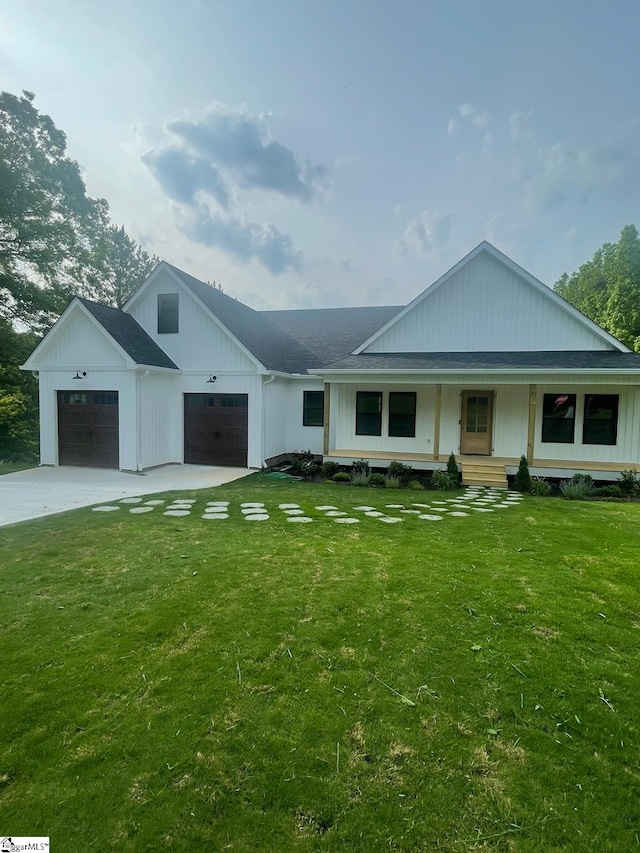 view of front of property with covered porch, a garage, and a front yard