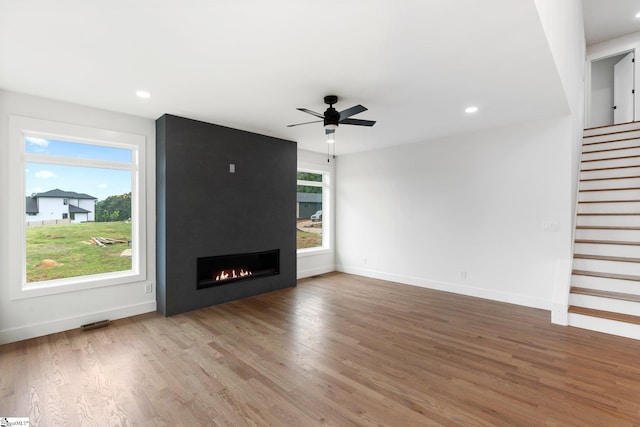 unfurnished living room featuring wood-type flooring, ceiling fan, and a fireplace