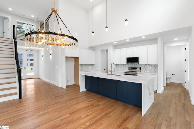 kitchen featuring light wood-type flooring, appliances with stainless steel finishes, white cabinetry, and sink