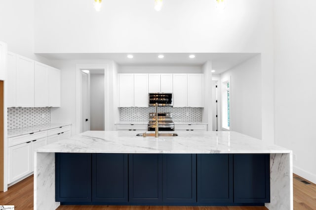 kitchen featuring appliances with stainless steel finishes, tasteful backsplash, a center island with sink, and white cabinetry