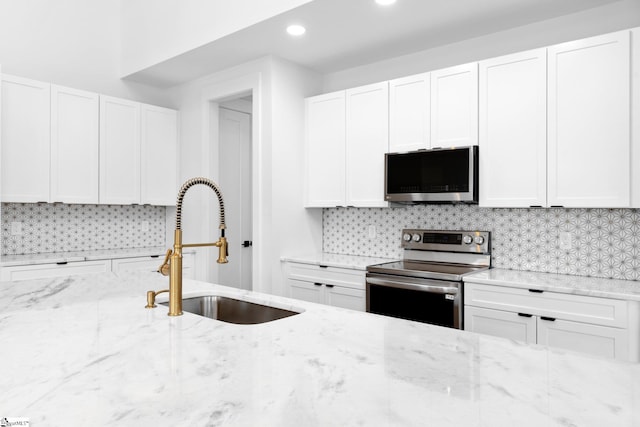 kitchen featuring tasteful backsplash, appliances with stainless steel finishes, and white cabinetry