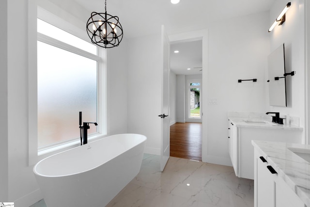 bathroom with a washtub, an inviting chandelier, tile floors, and vanity