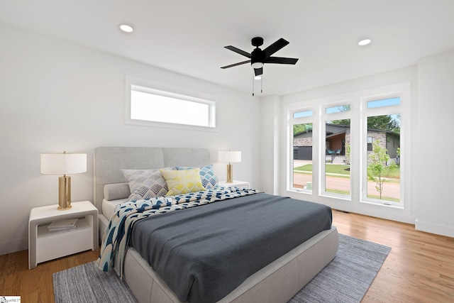 bedroom with ceiling fan, hardwood / wood-style floors, and multiple windows