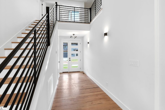 hall featuring french doors, hardwood / wood-style flooring, and a high ceiling