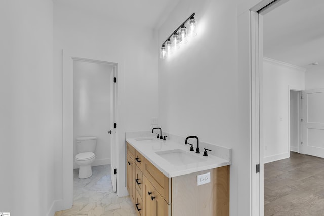 bathroom with double vanity, toilet, baseboards, and a sink