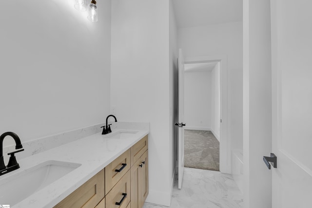 full bath with a sink, baseboards, marble finish floor, and double vanity