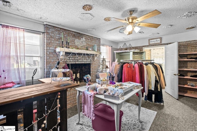 living room with a brick fireplace, ceiling fan, brick wall, a textured ceiling, and carpet floors