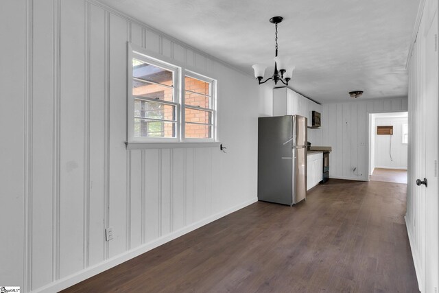 unfurnished dining area featuring a notable chandelier and dark hardwood / wood-style flooring