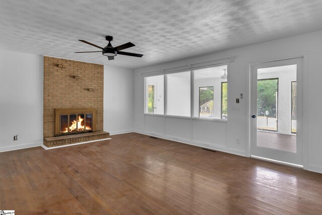 unfurnished living room featuring a healthy amount of sunlight, dark hardwood / wood-style floors, and a brick fireplace