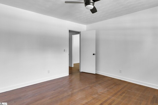 spare room with dark hardwood / wood-style flooring and ceiling fan