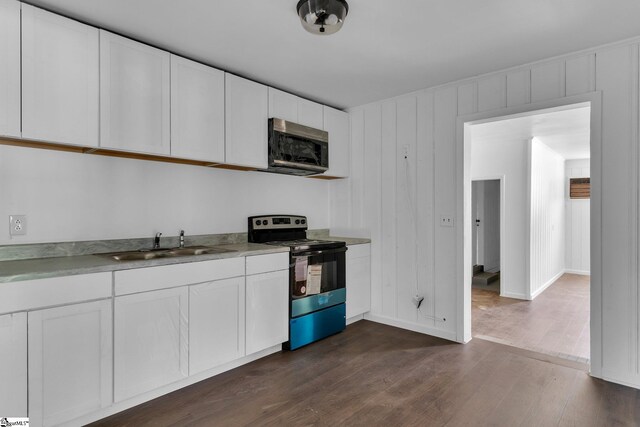 kitchen with appliances with stainless steel finishes, sink, white cabinets, and dark wood-type flooring