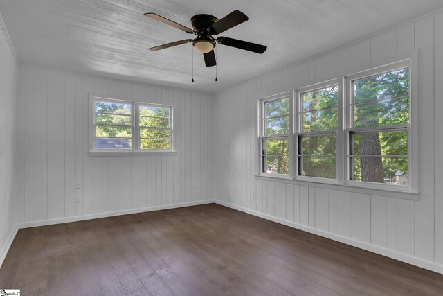 empty room with dark hardwood / wood-style floors, ceiling fan, and a healthy amount of sunlight