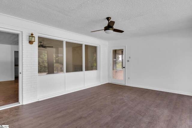 spare room with ceiling fan, dark hardwood / wood-style flooring, a textured ceiling, and brick wall