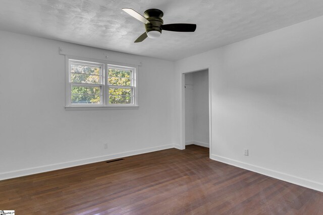 empty room featuring dark wood-type flooring and ceiling fan